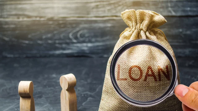 Loan concept — money bag under a magnifying glass